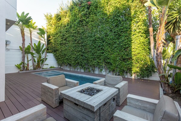 Una terraza con un jacuzzi, asientos al aire libre y una pared verde exuberante.