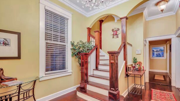 A staircase with wooden railings and a handrail, leading to an upper floor. - Historic Downtown Victorian Home Near Forsyth (Savannah)