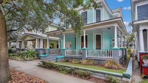 A row of two-story houses with front porches, a sidewalk, and a tree. - Historic Downtown Victorian Home Near Forsyth (Savannah)