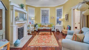 A living room with a fireplace, a sofa, a coffee table, and a patterned rug. - Historic Downtown Victorian Home Near Forsyth (Savannah)