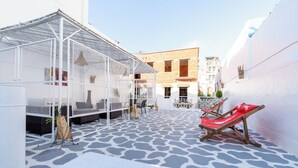 A covered outdoor seating area with a patterned floor, white walls, and a building in the background. - Kasbah Dream - Great Location in Tangier. (Tangier)