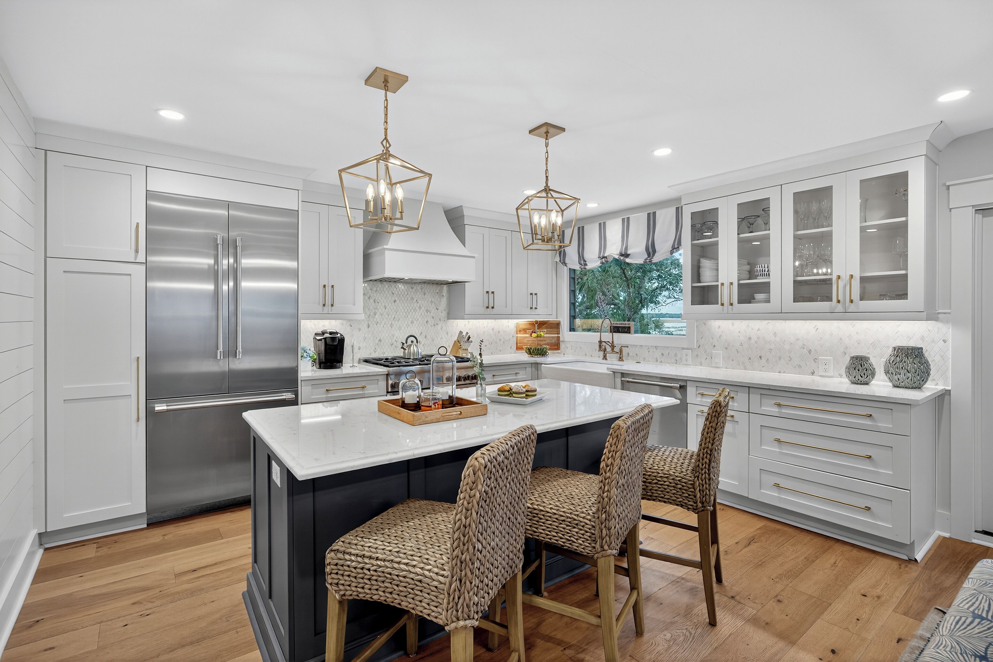A modern kitchen with white cabinetry, a large island, and a stainless steel refrigerator.
