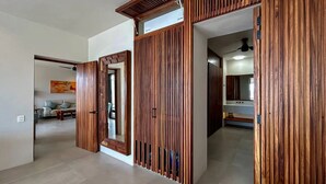 Ein Korridor mit Holzwandverkleidung, einem Spiegel und einer Tür zu einem Raum mit einer Couch und einem Gemälde.
