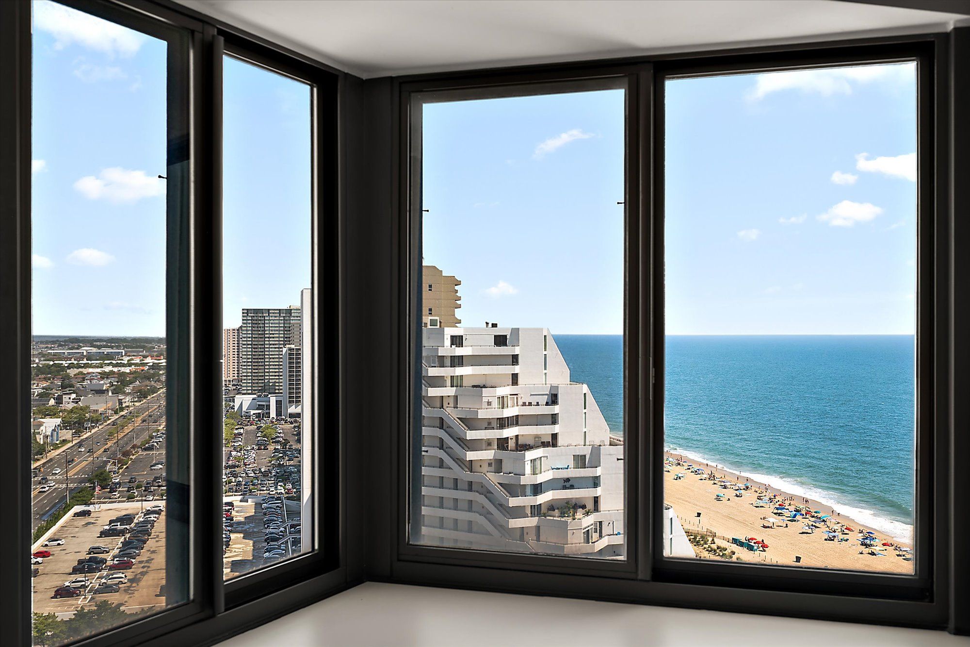 A corner room with a view of a beach and a parking lot.