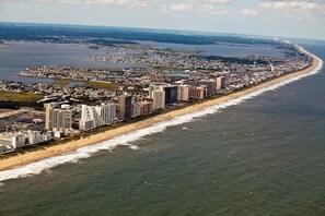 Vista aérea de una ciudad costera con una extensa playa, edificios altos y una zona urbana densa.