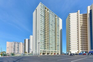 A high-rise hotel with multiple floors, a parking lot in front, and a clear blue sky. - Quay - Luxury Penthouse Condo! (Ocean City)