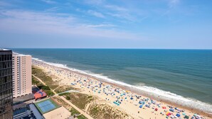 Una playa con numerosos paraguas y un edificio al frente.