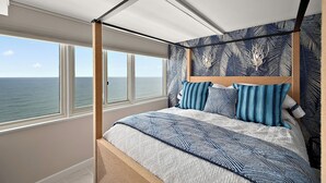 Un dormitorio con un ventanal grande, una cama con dosel y vistas al mar.