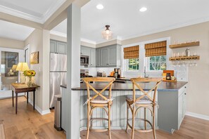 A modern kitchen with a central island, bar stools, and a breakfast bar.