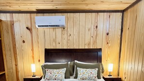 A wooden-paneled room with a bed, two bedside tables with lamps, and a ceiling vent. - 66 Tiny House (Clinton)