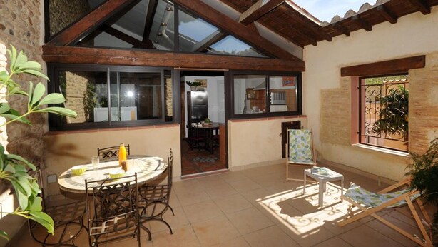 A covered patio with a table and chairs, a grill, and a view of the interior through a glass door. - GRENIER - PERPIGNAN - Gîte (PERPIGNAN)