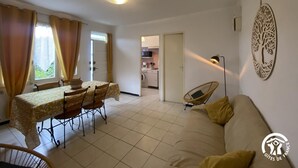 A compact living space with a dining area, a sofa, and a kitchen in the background. - Le coscollet 1 - ILLE-SUR-TET (ILLE-SUR-TET)