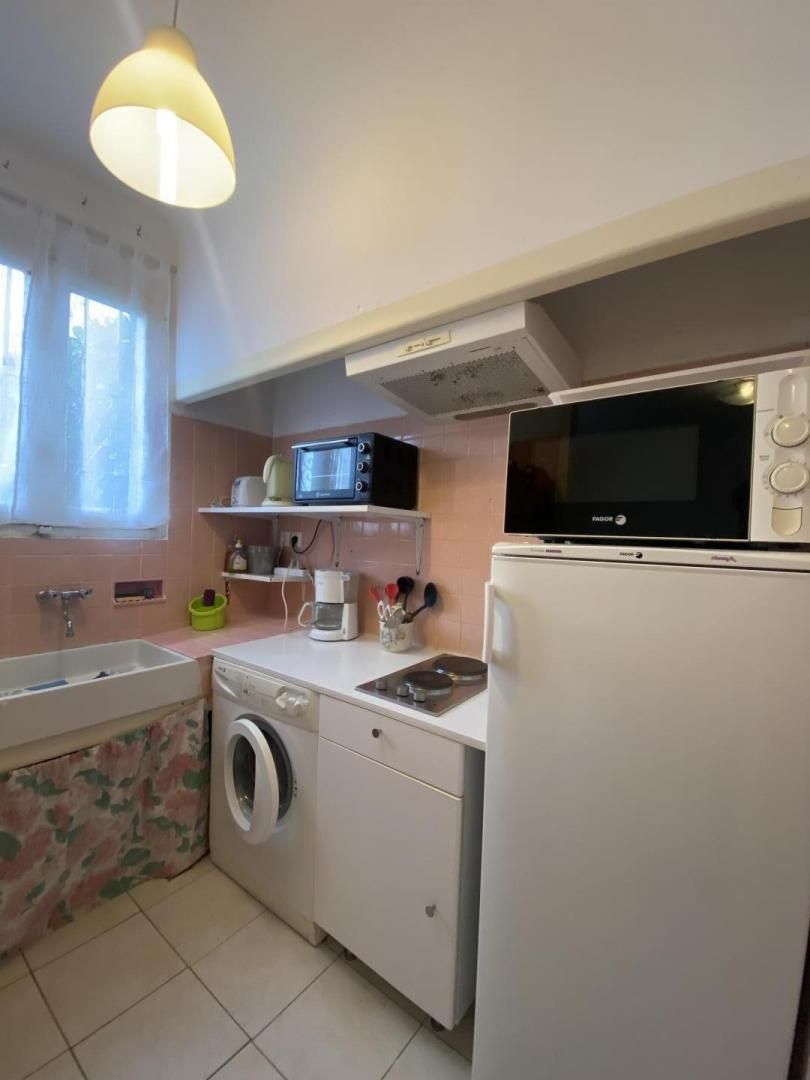 A compact kitchen with a washing machine, microwave, and a small sink.