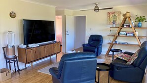 Ein Wohnzimmer mit Flachbildfernseher, Ledersofas, einer Holzkommode, einem Hängeschrank und einem Deckenventilator.