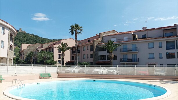 A swimming pool surrounded by a white fence, with a clear blue sky above. - Pause Colliourencque (COLLIOURE)