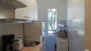 A compact kitchen with white cabinets, a stainless steel sink, a coffee maker, and a toaster. - Pause Colliourencque (COLLIOURE)