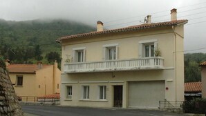 Un bâtiment à deux étages doté d’un balcon à l’étage supérieur, d’une porte de garage et ayant une chaîne de montagnes en toile de fond.