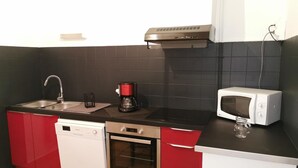 A compact kitchen with a dishwasher, oven, coffee maker, and microwave.