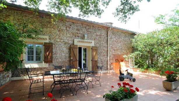 A stone building with a patio, outdoor seating, and potted plants.