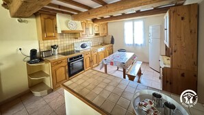 A kitchen with wooden cabinets, a tiled backsplash, a microwave, a sink, and a dining table with chairs.
