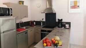 A modern kitchen with stainless steel appliances, a microwave, a coffee maker, and a fruit display. - L'arbousier - SAINT CYPRIEN (SAINT CYPRIEN)