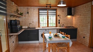Cocina compacta con comedor, que incluye un fregadero, estufa y una ventana con persianas.
