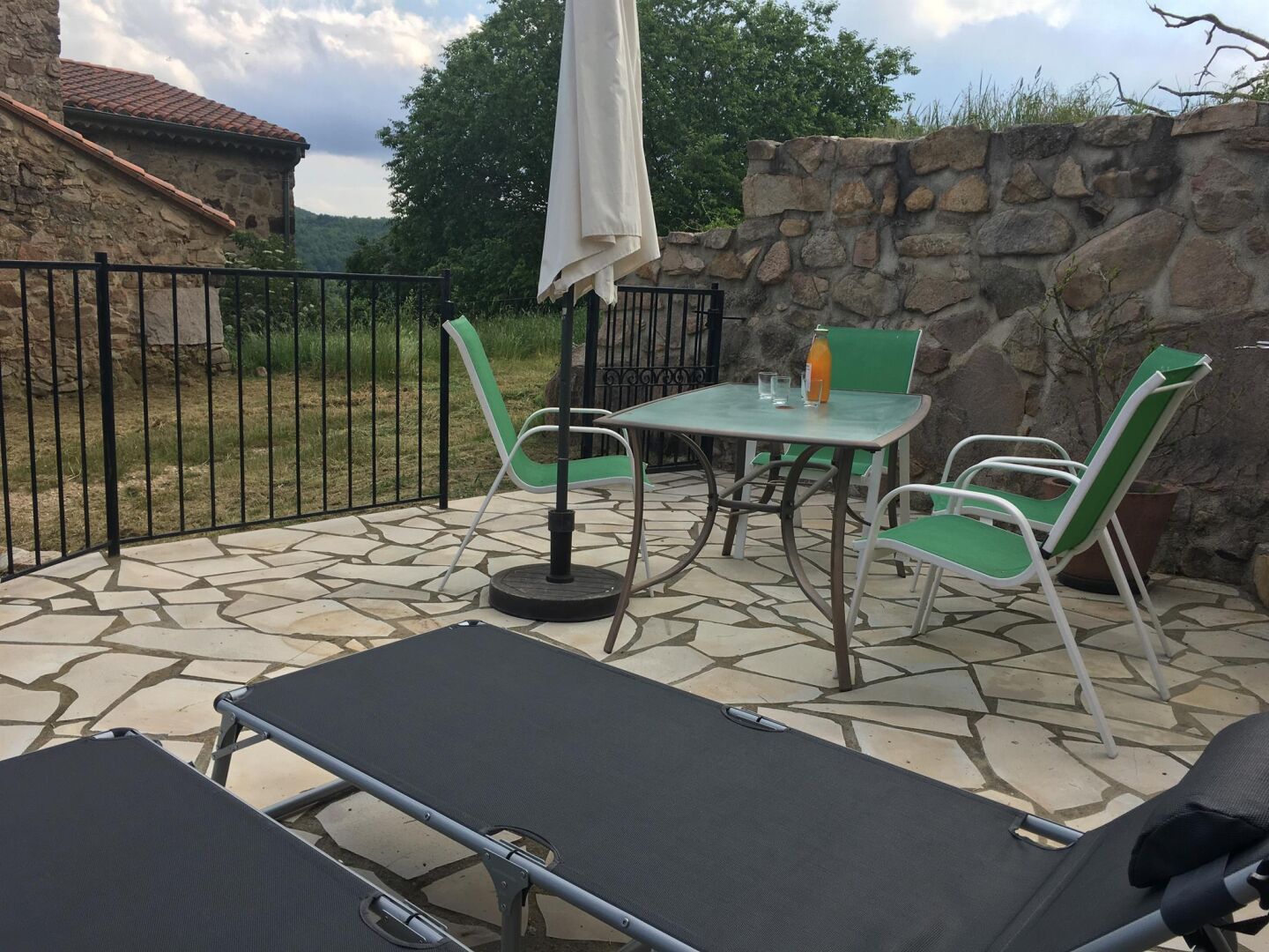 Un patio al aire libre con suelo de piedra, una mesa con sillas y un sillón reclinable.