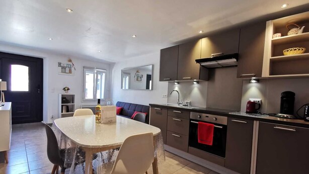 A modern kitchen with a dining area, featuring a table with chairs, a built-in oven, and a sink.