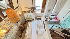A bedroom with a bed, a small table, a bench, a hanging light, and a view of the outside. - Colonial Loft Studio in the best location in the walled city of Ctg. (Cartagena de Indias)