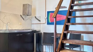 A kitchen with a wooden staircase, a hanging light fixture, and a colorful painting on the wall. - Colonial Loft Studio in the best location in the walled city of Ctg. (Cartagena de Indias)