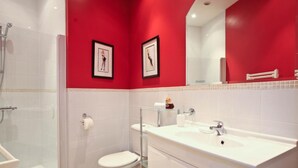 A modern bathroom with a white sink, toilet, and shower.