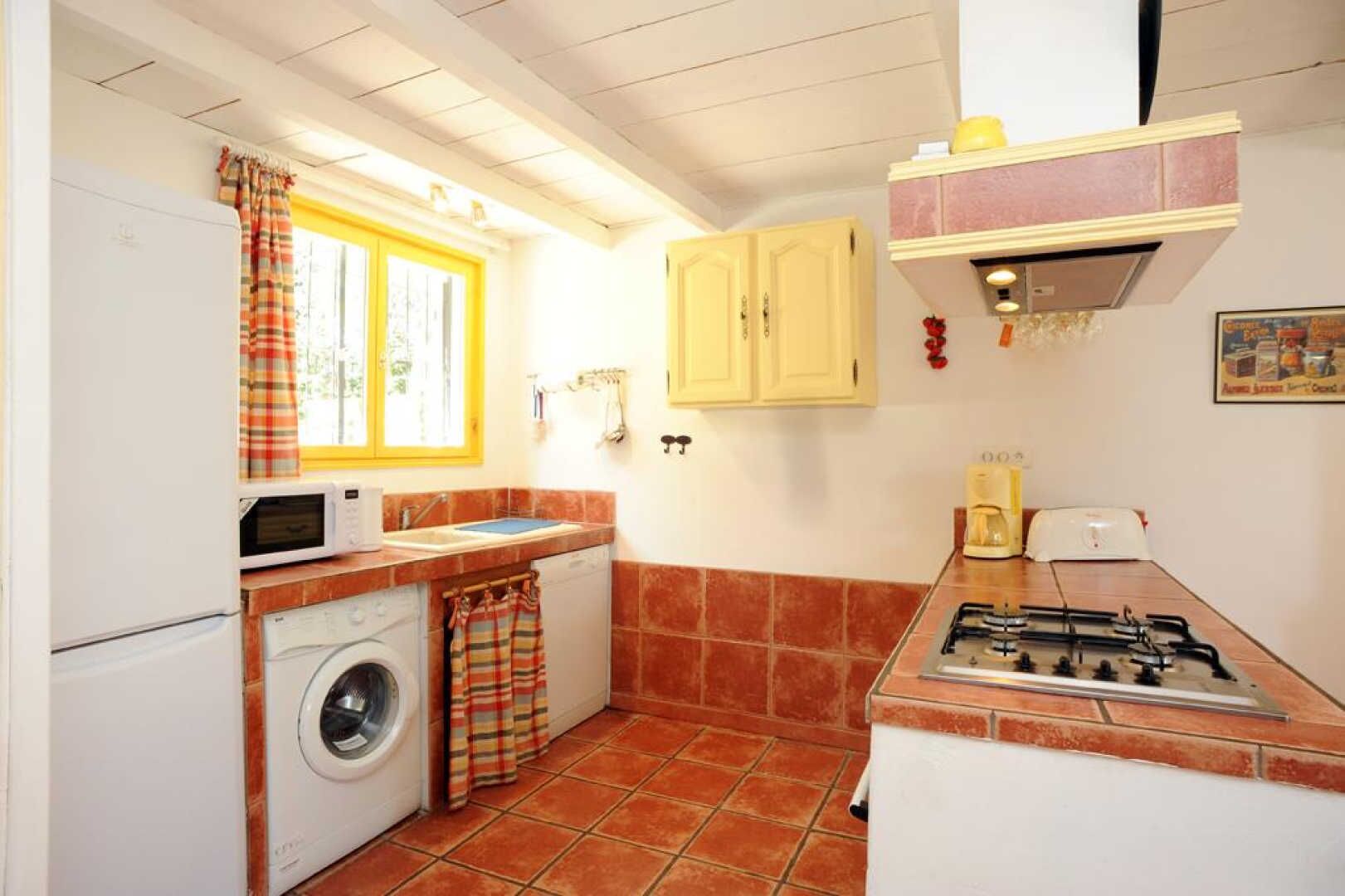 A compact kitchen with a washing machine, microwave, sink, and gas stove.