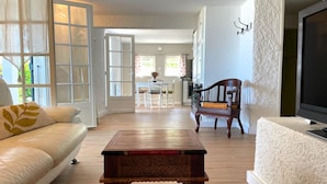 A living room with a wooden coffee table, a white sofa, and a television on a stand. - Les micoucouliers - LAROQUE-DES-ALBERES (LAROQUE-DES-ALBERES)
