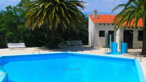 A swimming pool with clear blue water, surrounded by a white building with a red roof and palm trees. - Les micoucouliers - LAROQUE-DES-ALBERES (LAROQUE-DES-ALBERES)
