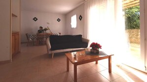 A living room with a sofa, a wooden coffee table, and a dining area with a table and chairs.