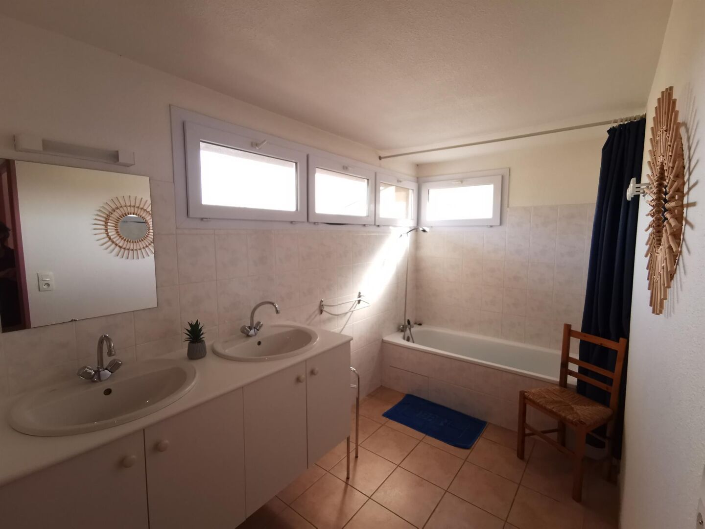 Een badkamer met twee wastafels, een bad, een douche, een spiegel en een raam.