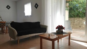 A living room with a sofa, a coffee table, and a window with sheer curtains.