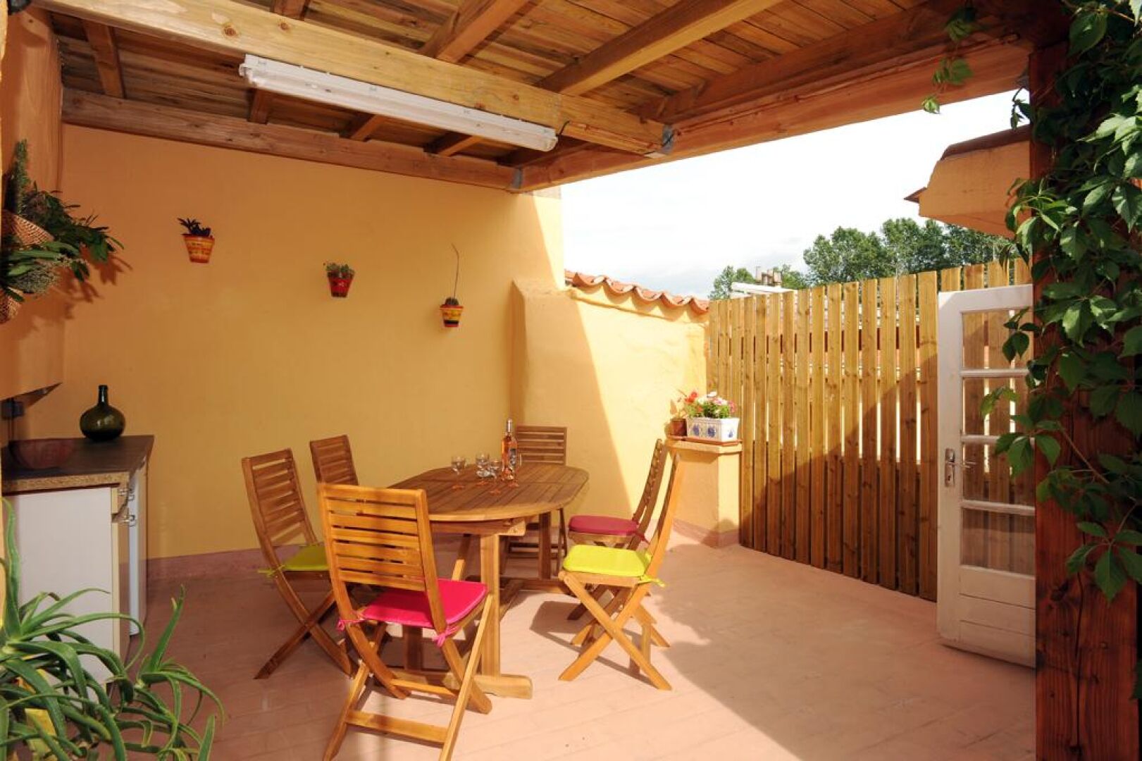 A patio with a wooden table and chairs, a small cabinet, and a door.