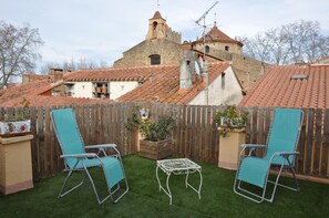 A backyard with two blue lawn chairs, a small white table, and a wooden fence. - Casa Puig - CERET - Gîte (CERET)