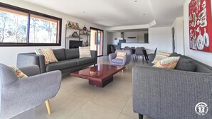 A modern living room with a sofa, armchairs, a coffee table, and a dining area with chairs and a table. - Eucalyptus - THUIR - Gîte (THUIR)