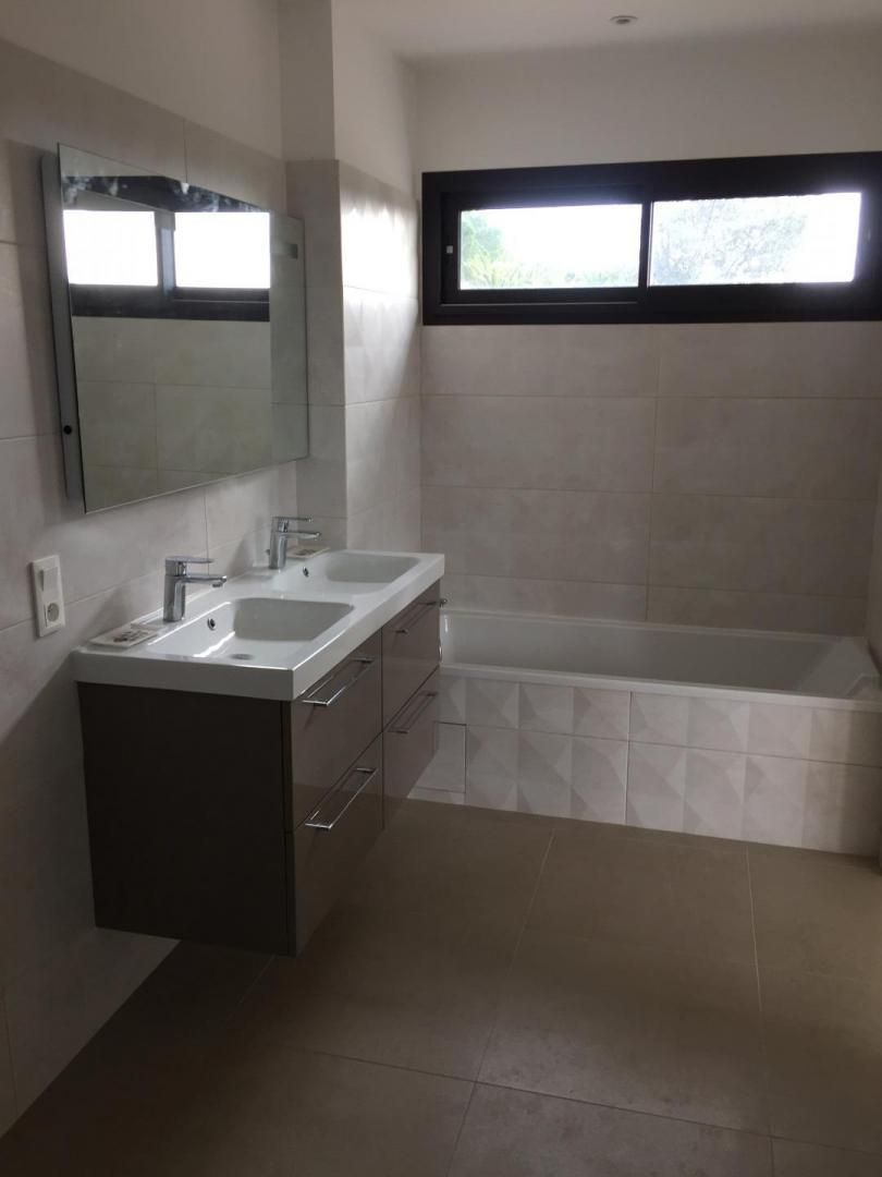 A modern bathroom with a double sink vanity, a large mirror, and a bathtub.