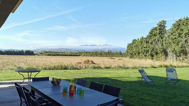 An outdoor patio with a table and chairs, a grassy area, and a view of mountains. - Eucalyptus - THUIR - Gîte (THUIR)