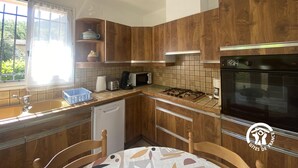 A kitchen with wooden cabinets, a gas stove, a microwave, and a dishwasher. - Hortensias - ARLES-SUR-TECH (ARLES-SUR-TECH)