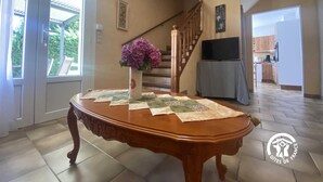 A dining area with a wooden table, a vase of flowers, and a staircase leading to a kitchen. - Hortensias - ARLES-SUR-TECH (ARLES-SUR-TECH)