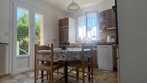 A kitchen with a dining table and chairs, a refrigerator, and cabinets. - Hortensias - ARLES-SUR-TECH (ARLES-SUR-TECH)