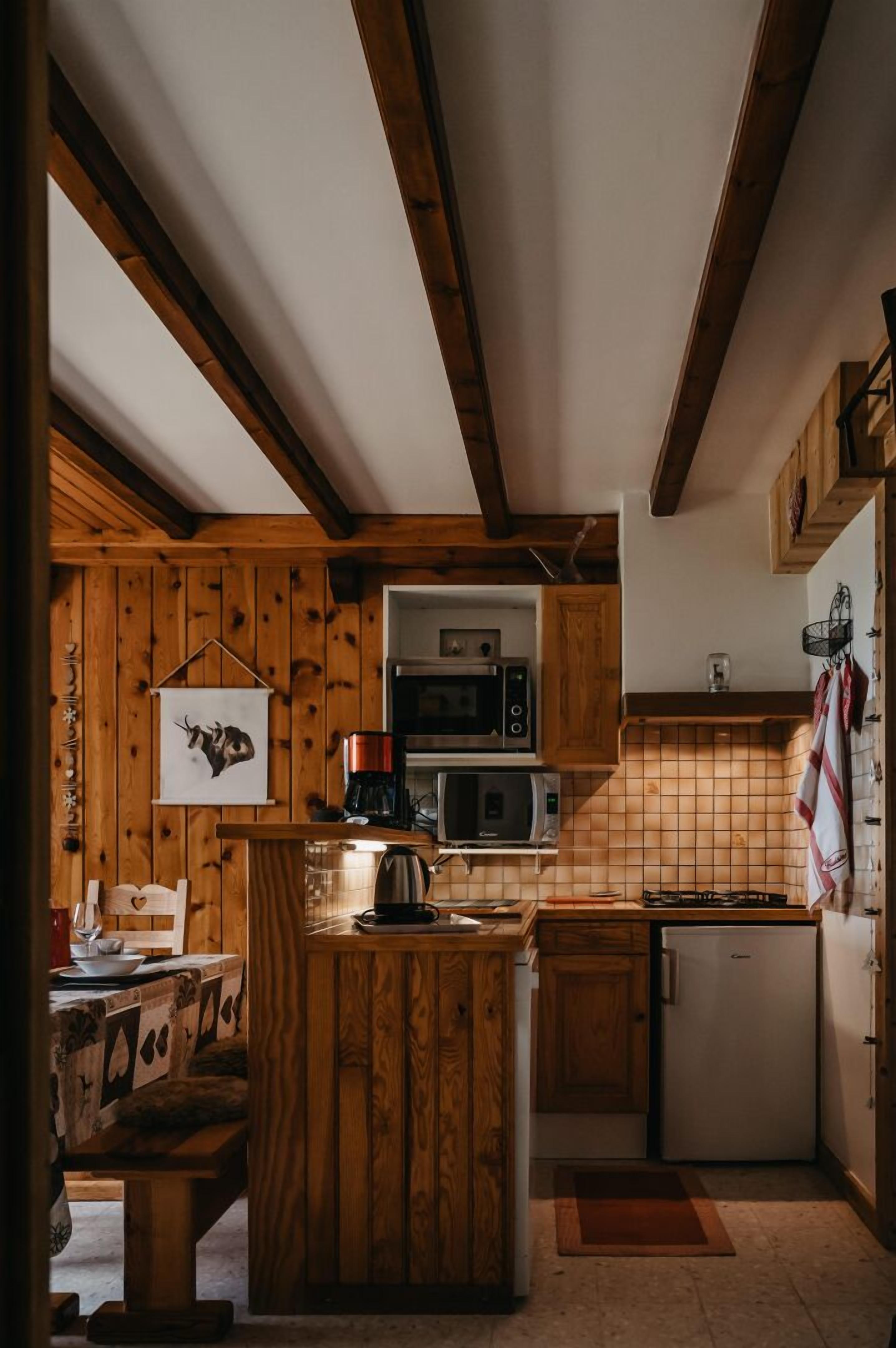 A rustic kitchen with wooden cabinets, a central island, and a microwave.
