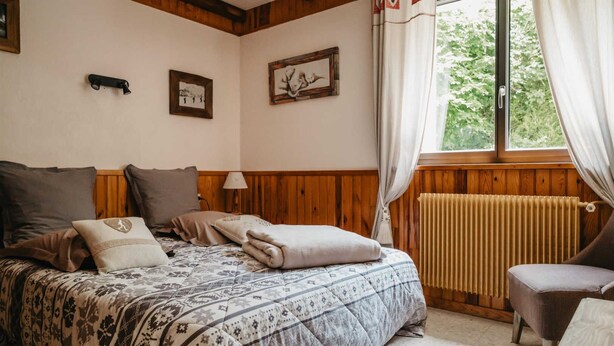 Une pièce confortable avec un lit, une chaise et une fenêtre avec des rideaux.