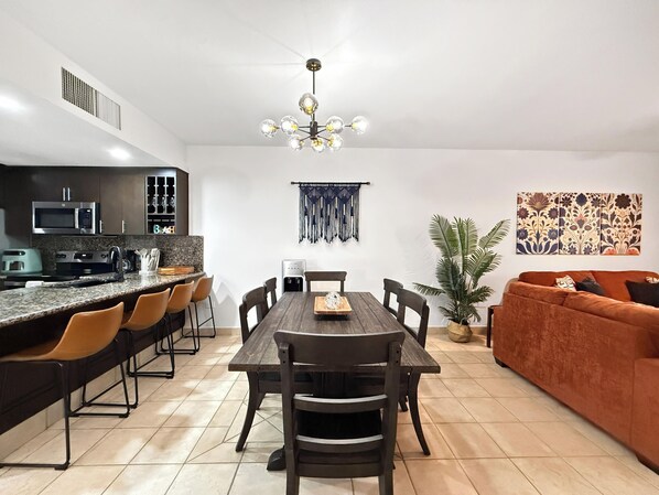 Una cocina moderna con comedor, un sofá y un elemento decorativo en la pared.