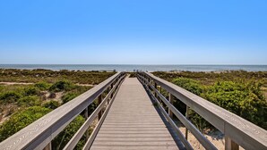 Una pasarela de madera que conduce a una playa con cielo despejado.