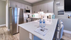 Una cocina moderna con electrodomésticos de acero inoxidable, armarios grises y una isla central con asientos.